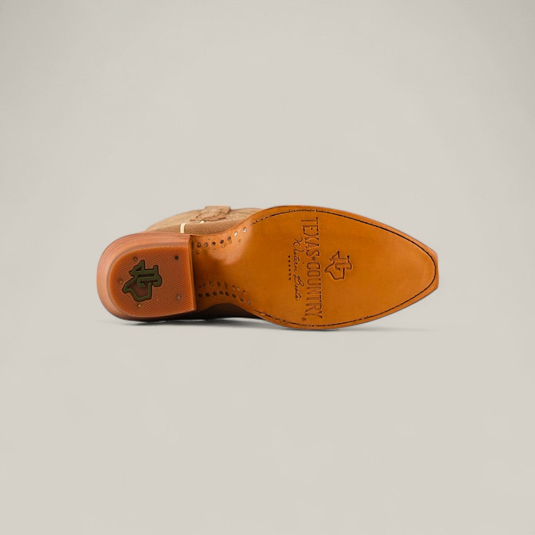 The Miranda Suede Khaki Leather Boot is shown from the sole, displaying intricate stitching, a snip toe, the Texas Country logo, and branding details on the bottom.