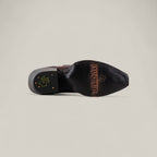 The Miranda Clayton Brownie Leather Sole boot features a TEXAS COUNTRY engraving and cross logo on the sole, plus a black and gold heel emblem—ideal for fans of classic, mid-shaft, snip-toe leather sole boots.