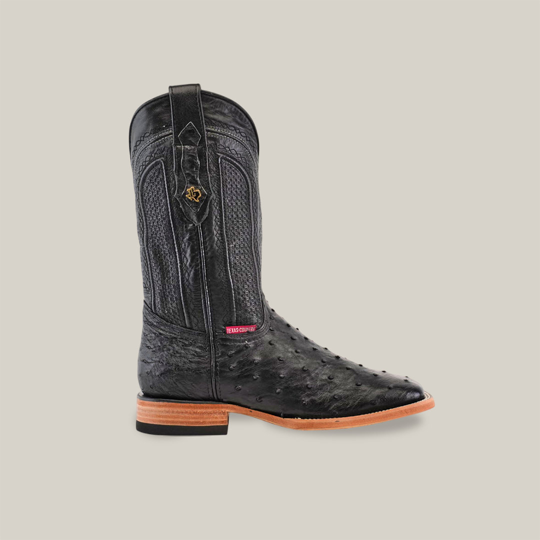 A single Exotic Full Quilt Ostrich Black Square Toe boot is shown on a light grey background, featuring an ostrich leather design, a wooden heel, and a small emblem on the shaft.