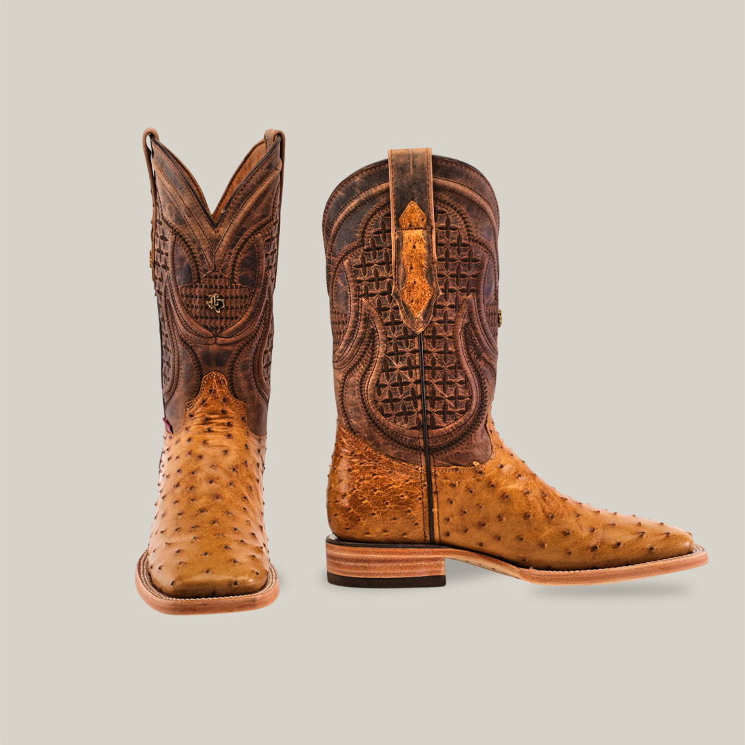 A pair of Exotic Full Quilt Ostrich - Fawn - Square Toe cowboy boots with intricate stitching is showcased on a light gray background. The left boot angles forward and the right is in profile, both flaunting a rich brown and tan finish.