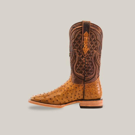 The Exotic Full Quilt Ostrich - Fawn - Square Toe boot displays intricate shaft patterns and an ostrich leather texture on the foot. It has a wooden heel and sole, all set against a plain beige background.