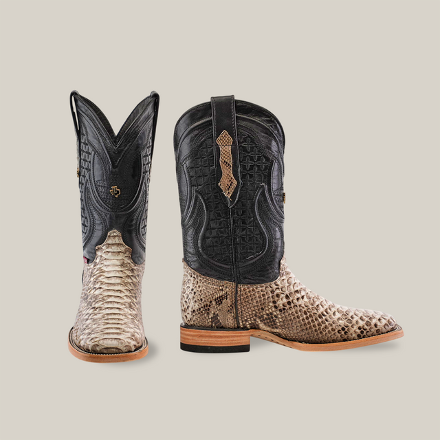 A pair of Exotic Python - Natural - Square Toe boots on a neutral background. These cowboy boots feature black leather uppers with intricate stitching and light brown, python-like textured scales on the lower part, complemented by wooden heels and flat, brown soles.