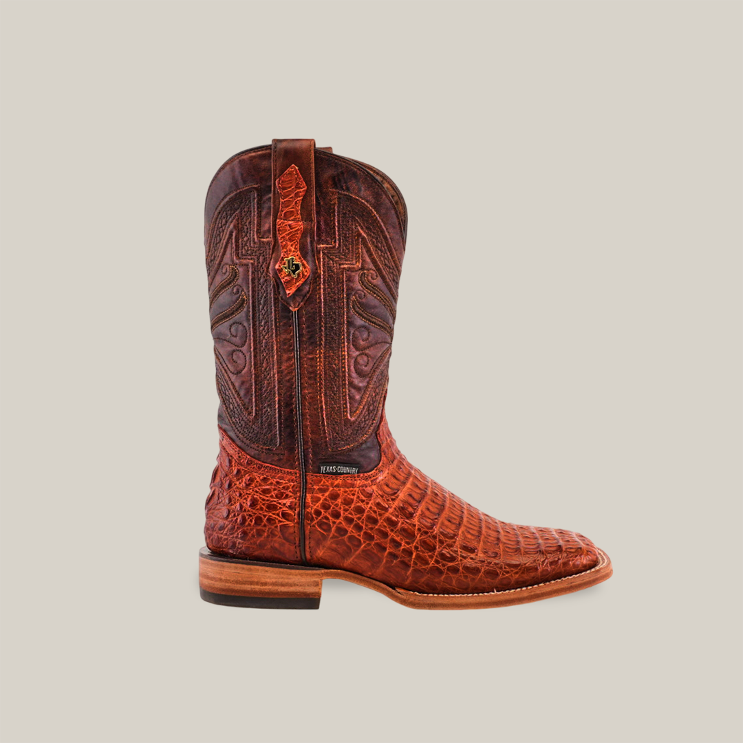 A single Exotic Caiman Horn Back cowboy boot in brandy, with intricate patterns and stitching, is displayed on a neutral background. The boot features a textured crocodile-inspired lower section from Caiman leather and a smooth upper shaft with a classic square toe design.