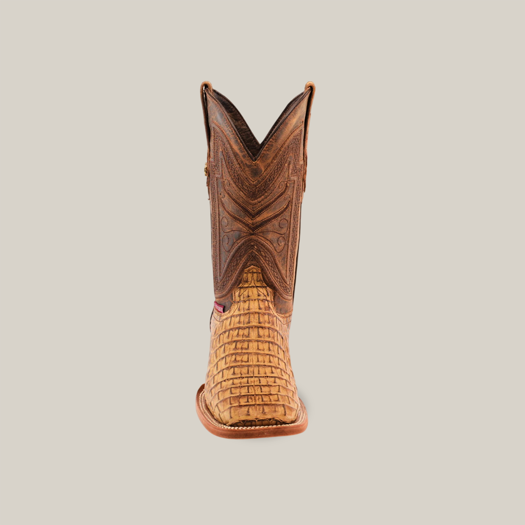 A front view of Exotic Caiman Horn Back - Biza Camel boots featuring a textured tan lower section and dark brown upper, with intricate stitching and patterns on a plain light grey background.