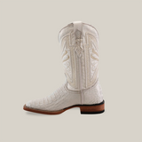 The Exotic Caiman Horn Back boot in white features exquisite craftsmanship with intricate embroidery and a brown sole. Its detailed stitching and square toe highlight the premium Caiman leather construction, standing out against the plain beige backdrop.