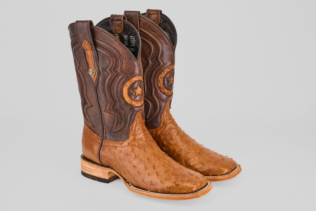 The Exotic Full Quilt Ostrich - Brandy Brucciato - Square Toe boots feature light brown ostrich leather with darker brown uppers, classic western shaft stitching, and stylish stacked wooden heels.