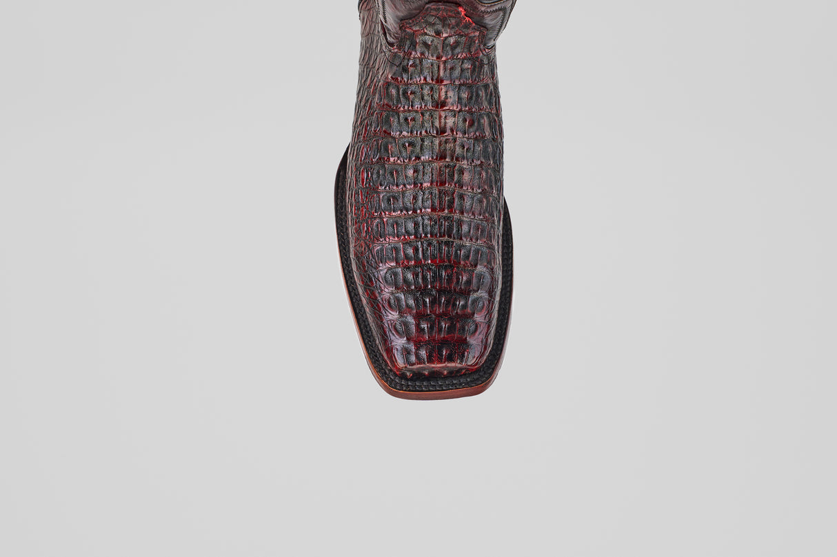 A close-up top view of the Exotic Caiman Hornback - Blackcherry boot highlights its Rodeo Toe and crocodile-patterned leather, photographed against a plain gray background—ideal for fans of this exotic style.