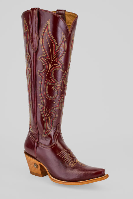 The Allison Blackberry - Tall Shaft - Snip Toe boot, in burgundy leather with decorative stitching, a pointed toe, and a medium wooden heel, is displayed against a plain light gray background.