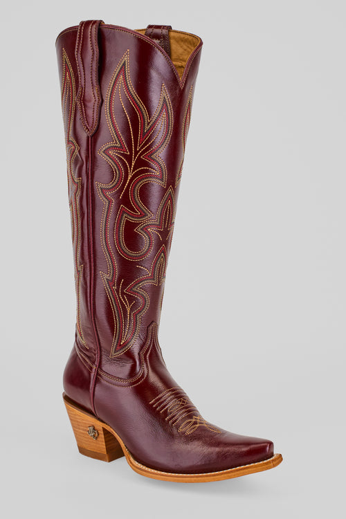 The Allison Blackberry - Tall Shaft - Snip Toe boot, in burgundy leather with decorative stitching, a pointed toe, and a medium wooden heel, is displayed against a plain light gray background.