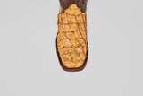 A top view of the Conor - Buttercup - Rodeo Toe boot features textured yellowish-brown leather reminiscent of exotic skin, set against a plain gray background, emphasizing its distinctive western style.