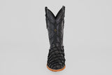 A single Conor - Matte Black - Roper Toe boot made from black pirarucu fish leather, featuring detailed stitching and textured scales on the lower section. Viewed from the front against a plain light gray background with a tan sole.