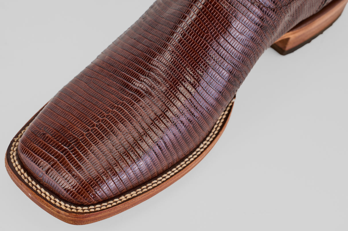 Close-up of the Blaze – Brown – Square Toe Cowboy Boot toe, crafted from lizard leather with beige stitching and a wooden sole, set against a plain light background.