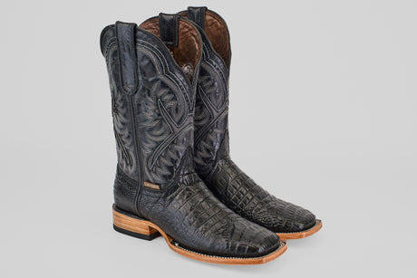 The Caiman Belly Black - Embossed Leather - Square Toe (E423) boots feature intricate stitching, a textured reptile-like pattern, light brown wooden soles, and square toes, displayed on a plain background.