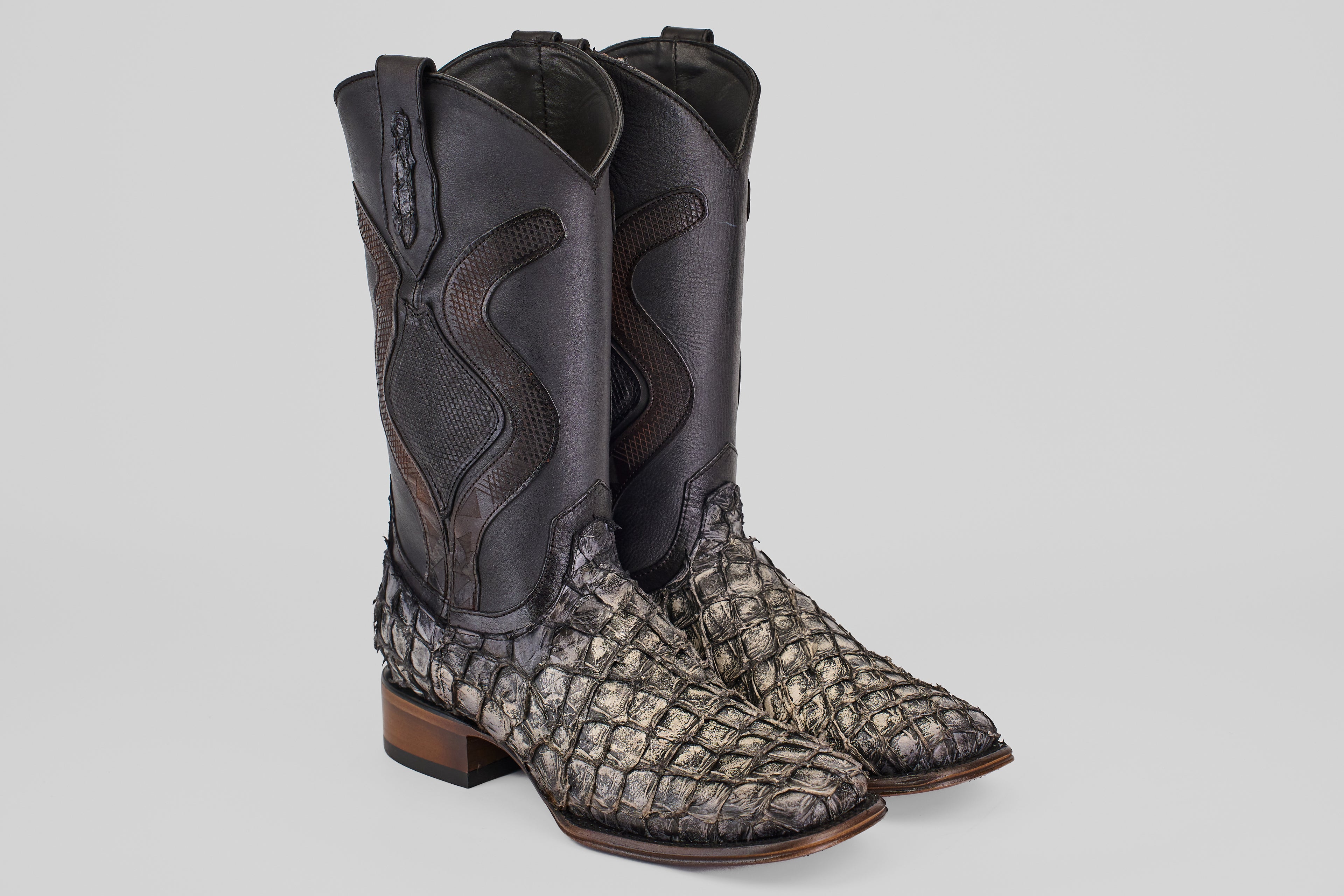 Introducing the Conor Platinum - Newspaper - Square Toe (Diamond): cowboy boots with black leather shafts, textured gray pirarucu leather feet, and brown wooden soles—ideal western boots for men wanting standout style.