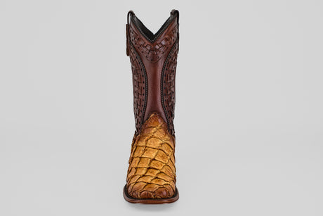 The Conor Platinum - Buttercup - Square Toe (Herradura) boot features a dark brown, intricately tooled upper and a light brown pirarucu-textured lower front, shown from the front against a plain gray background.