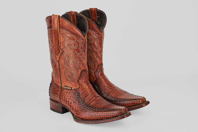 A pair of Lizard Cogñac - Embossed Leather - Versy Toe (E201) cowboy boots, showcasing intricate stitching and patterned texture with pointed toes and block heels, displayed against a plain light gray background.