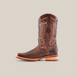 The Azkar Tan boot features a premium cowhide leather design with intricate shaft stitching, showcased in profile on a white background. It has a slip-resistant wooden sole and rounded rodeo toe.