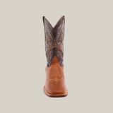 The Cater Honey - Square Toe boot stands upright against a plain white background, showcasing intricate stitching on the shaft. Crafted by artisan bootmakers, it features a blend of dark and light brown premium cowhide with decorative patterns demonstrating unmatched craftsmanship