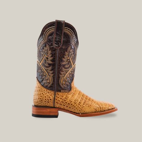 The Caiman Belly Print Orix - Square Toe boot features a single cowboy boot design with a square toe, an intricately leaf-patterned dark brown shaft, and a textured light brown leather foot resembling caiman belly. It is complemented by its wooden heel and light-colored sole, set against a white background.