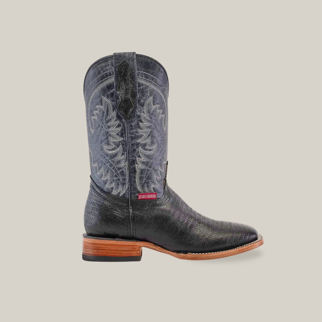 The Lizard Print Black - Square Toe cowboy boot features a premium black textured finish with ornate shaft stitching. It has a brown leather sole, low heel, and a red and white side label, elegantly highlighted against a plain white background.