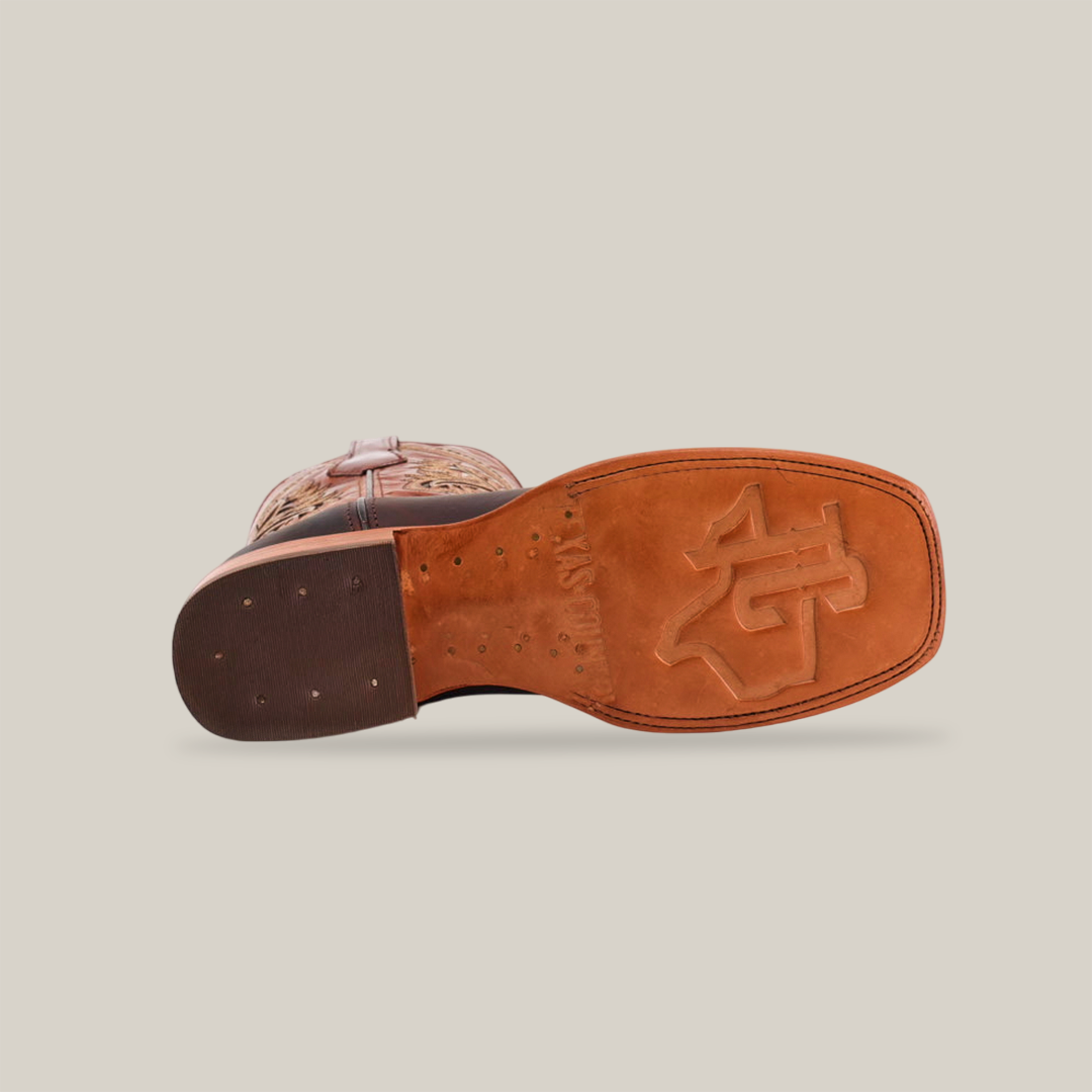 A bottom view of the Azkar Moka - Square Toe cowboy boot reveals a tan cowhide leather sole with an embossed logo, featuring a stacked heel and visible perimeter stitching. The worn leather offers a rustic touch.