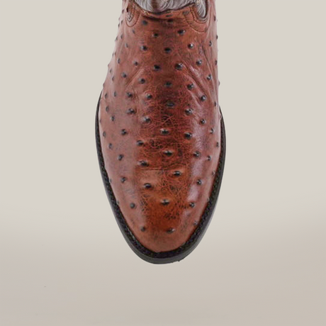 The Karoo Ostrich Print Chocolate - Round Toe boot, showcasing its luxury leather with distinctive texture and dark-edged sole, stands out against a white background.