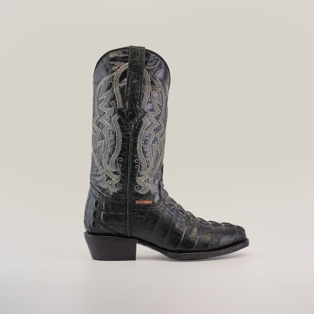 The Crocodile Tail Print Black - Round Toe is a black cowboy boot crafted in luxurious cowhide leather with intricate silver stitching and a glossy finish. It is displayed against a plain white background, featuring meticulous craftsmanship and a sturdy heel.