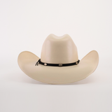 The 1000X Chihuahua Straw Hat, a cream-colored cowboy hat with a wide brim and black braided band featuring metal accents, makes a bold fashion statement. Made from durable materials, this striking piece is showcased against a plain white background.