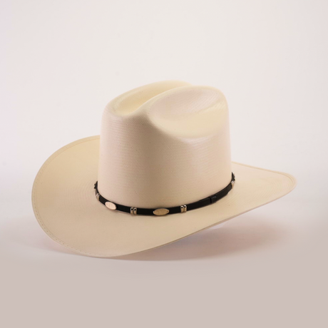 The 1000X Dos Carnales Straw Hat is a beige cowboy hat with a wide, curved brim and a black band featuring light decorative elements. Its exceptional quality and craftsmanship are highlighted against a plain background, making it an iconic accessory.