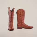 A pair of Grisly Brown - Rodeo Toe cowboy boots stands against a white backdrop. Made from premium cowhide, they showcase intricate stitching and a classic western design with pointed toes and stacked heels.