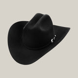 #color_black 
The Tony Lama 1000X from the Rodeo Special Offer Online is a fashion masterpiece, featuring a wide-brimmed black hat with a decorative silver buckle on the hatband, set against a plain gray background.