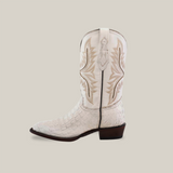 The Exotic Caiman Hornback - White - Round Toe boot features intricate embroidery on authentic caiman leather. It has a high shaft, a low wooden heel, and a textured crocodile pattern set against a plain beige background.