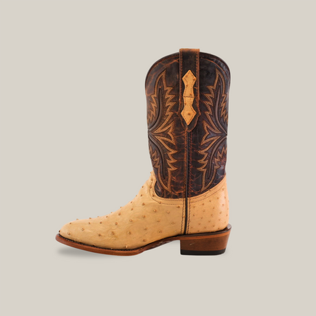 A single Exotic Full Quilt Ostrich - Orix - Round Toe boot against a plain backdrop. The boot combines ostrich leather with a textured light tan lower section, while the darker brown upper section boasts intricate stitching. Its short, squared heel embodies unmistakable cowboy style.