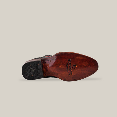 The image displays the sole of a Belvedere Exotic Python - Black - Round Toe mens dress shoe, capturing premium cowboy craftsmanship. It has a glossy brown finish with black textured material on the heel for grip and the Belvedere logo stamped in the center of its wooden section.