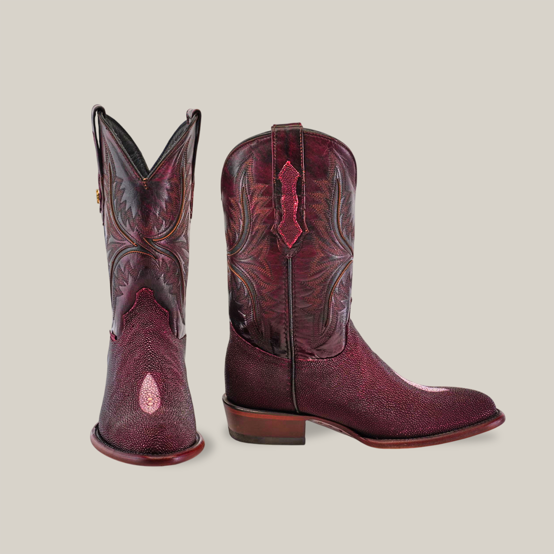 A pair of luxury Exotic Stingray - Wine cowboy boots crafted from exotic materials, showcasing intricate stitching and a polished finish, with one boot facing forward and the other angled. They feature a sturdy heel and round toe against a plain background.