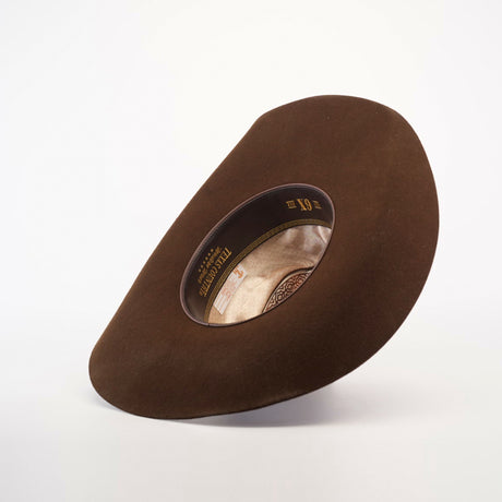 The 6X Doble SS Brown hat, with its wide suede brim and circular opening, embodies classic Western style. Its interior label attests to its quality. Displayed on a plain white background, this hat exudes traditional charm.