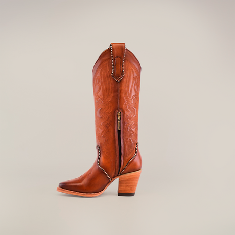 The Linda Tall Shaft Tan - J Toe, crafted from premium brown leather with intricate stitching and a side zipper, is displayed against a plain background. Part of the Platinum Collection, its wooden heel enhances the classic western style.