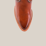 Top view of the Linda Tall Shaft Tan - J Toe cowboy boot, highlighting intricate heart and horseshoe stitching on the toe, with silver embellishments around the top. Set against a plain beige background.