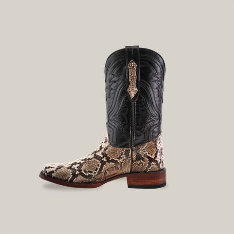 The Exotic Python - Natural - Rodeo Toe boots showcase a side profile with a black leather upper and brown snakeskin pattern on the foot, handcrafted with intricate stitching, pull strap, and wooden heel. These luxurious boots are set against a plain beige background.