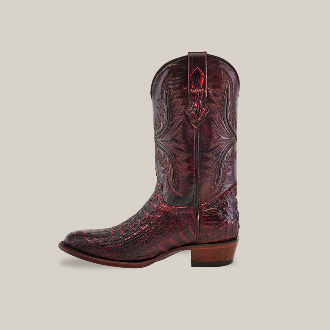 A detailed Exotic Caiman Hornback boot in black cherry is displayed against a simple background, featuring intricate stitching and a unique wooden heel.