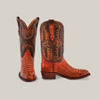 The Exotic Caiman Hornback - Brandy - Round Toe boots feature genuine caiman leather with intricate stitching and a crocodile-patterned lower part. The tall shaft has elaborate patterns and a slight heel, epitomizing true western wear. One boot stands upright while the other is slightly angled.