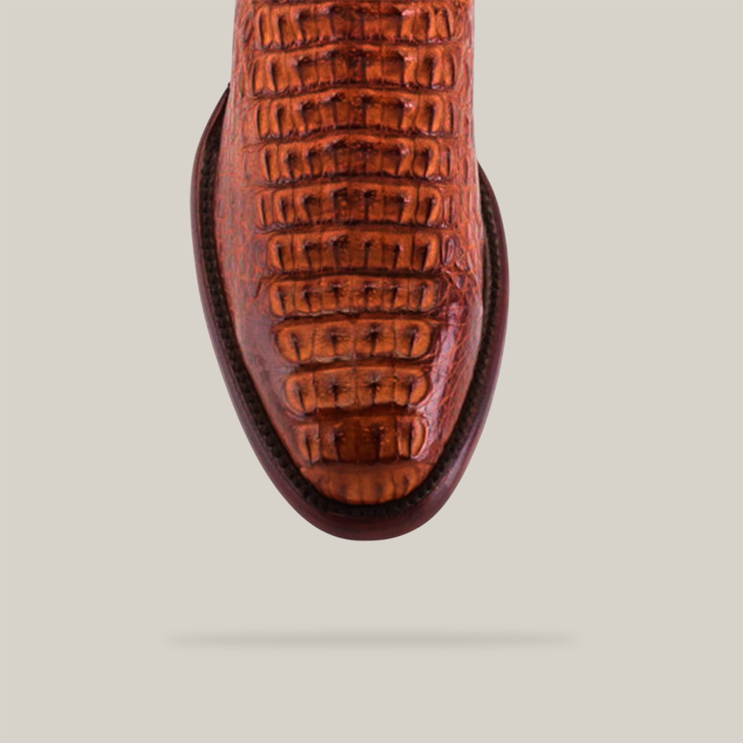 Close-up of the Exotic Caiman Hornback - Brandy with a round toe, showcasing its texture centered on a light beige background, capturing the authentic essence ideal for western wear enthusiasts.