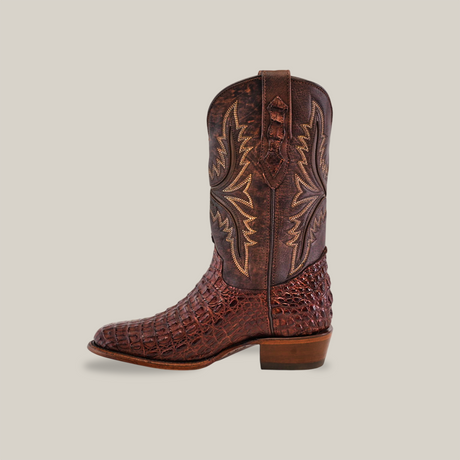 The Exotic Caiman Hornback - Brown - Round Toe boot is handcrafted, showcasing an intricate textured design with decorative shaft stitching, crafted from authentic caiman leather, and viewed from the side against a plain background.