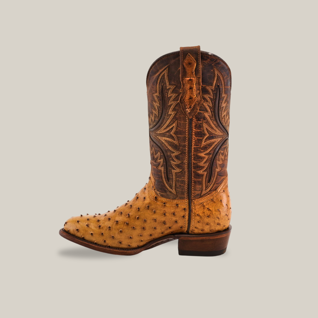 Side view of the Exotic Full Quilt Ostrich - Paja featuring a light brown ostrich leather lower and a darker brown upper with intricate stitching, showcasing its timeless Western heritage against a plain light gray background.