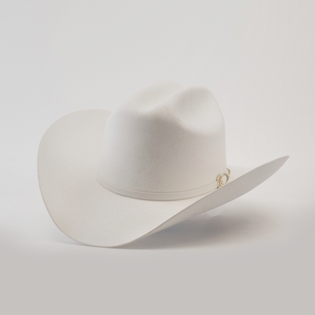 The 6X Real White hat is a luxury piece of Western headwear, featuring a wide brim and decorative band. Handcrafted from fur felt by skilled artisans, it is slightly tilted to accentuate its classic western style against a plain background.