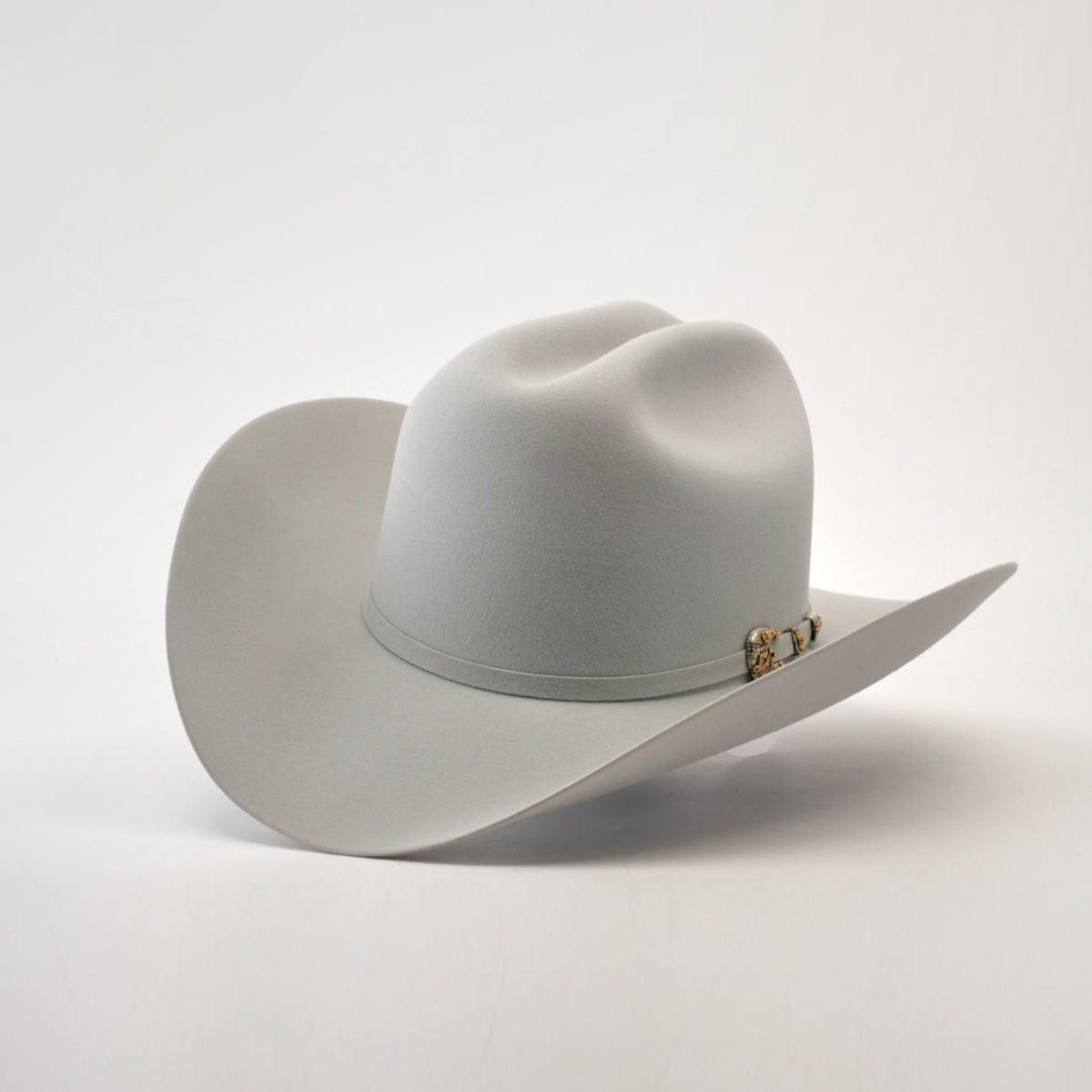 The 1000X Imperial Platinum is a light gray Larry Mahan cowboy hat with a wide brim, distinct crown crease, and decorative band with metal ornament, angled slightly on a plain backdrop, capturing the iconic western style.