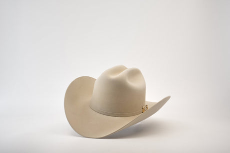 The 5X Dorado Belly, a beige cowboy hat crafted from fur felt with a wide brim and pinched crown, exudes timeless elegance against a plain white background.