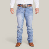 The lower half of a person is shown wearing Western blue straight fit embroidered jeans (W434), a white shirt, a brown leather belt with a large silver buckle, and brown cowboy boots against a plain background.