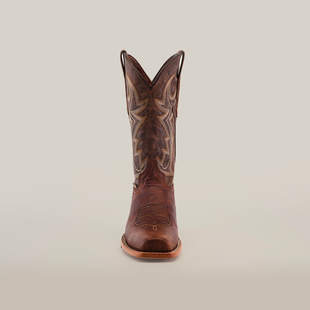 The Fresno Cogñac stands out on a plain white background with its cowhide leather construction and decorative stitching. The tall shaft features intricate patterns, capturing the rugged yet refined cowboy essence with a rounded wide cutter toe and stacked heel.