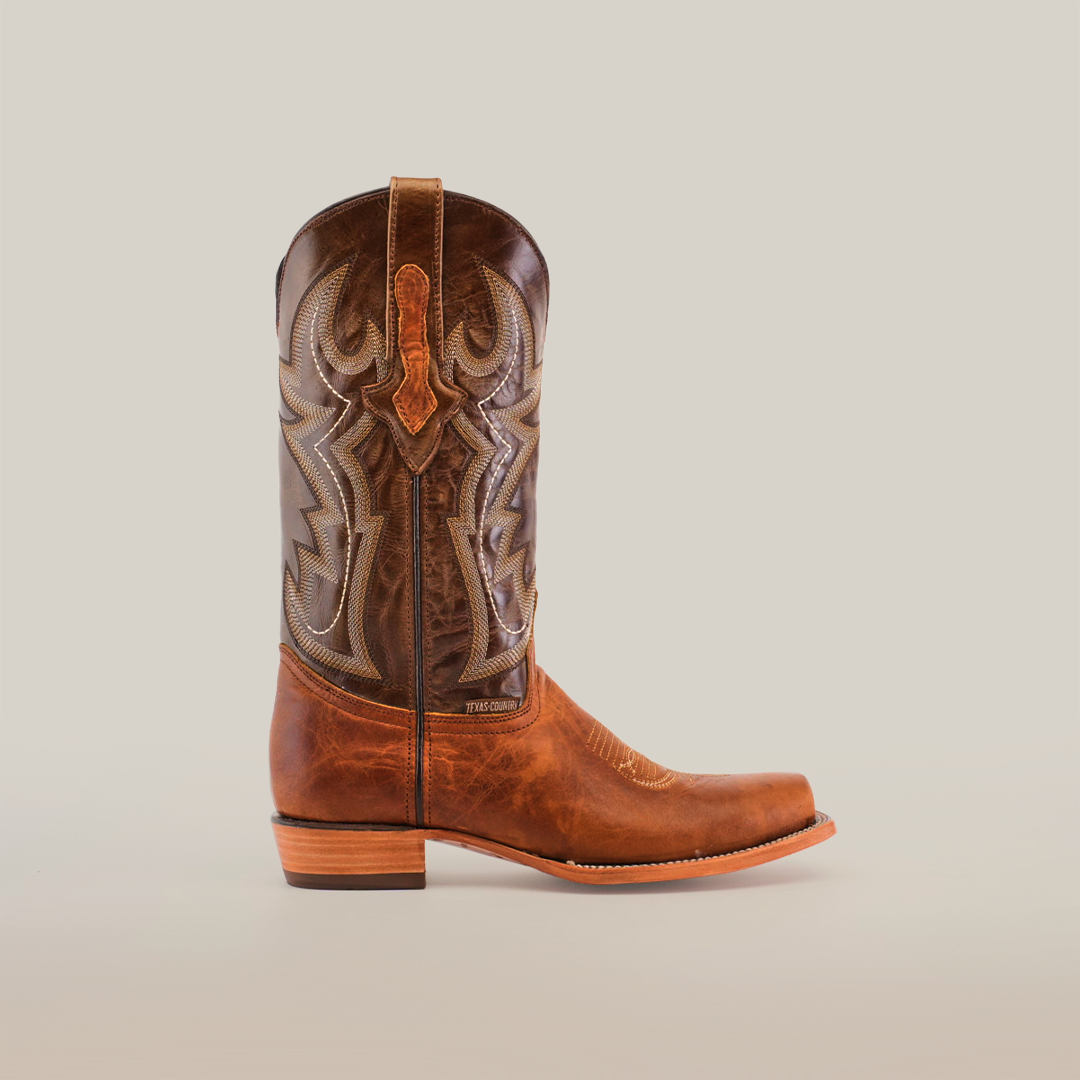 Side view of a Fresno Tan - Wide Cutter Toe cowboy boot, crafted from premium cowhide leather with intricate shaft stitching. It features a wooden heel and a wide cutter toe, embodying the authentic cowboy lifestyle against a plain white background.